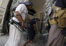 Guards walk through a damaged gate of the house of Brigadier Khaled al-Anduli, an army commander loyal to the Houthi movement, after it was hit by Saudi-led air strikes in Yemen's capital Sanaa, July 6, 2015. PHOTO BY REUTERS/Khaled Abdullah