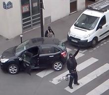 Gunmen gesture as they return to their car after the attack outside the offices of French satirical weekly newspaper Charlie Hebdo (seen at rear) in this still image taken from amateur video shot in Paris, January 7, 2015. PHOTO BY REUTERS/Reuters TV