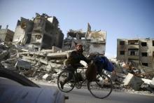 A handicapped man rides a bicycle past damaged buildings in the besieged town of Douma in eastern Ghouta in Damascus, Syria, March 1, 2018. PHOTO BY REUTERS/Bassam Khabieh