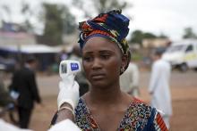 A health worker checks the temperature of a woman entering Mali from Guinea at the border in Kouremale, October 2, 2014. PHOTO BY REUTERS/Joe Penney