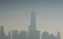 A helicopter flies over the Hudson River with One World Trade Center and Lower Manhattan in the background, on a hazy day in New York City, December 6, 2015. PHOTO BY REUTERS/Rickey Rogers