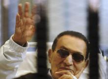 Former Egyptian President Hosni Mubarak waves to his supporters inside a cage in a courtroom at the police academy in Cairo, April 13, 2013. PHOTO BY REUTERS/Stringer