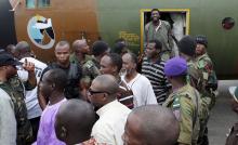 Cameroonian military personnel watch as freed hostages disembark from a military plane upon arriving at the Nsimalen International Airport in Yaounde, November 26, 2014. PHOTO BY REUTERS/Stringer