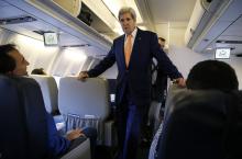U.S. Secretary of State John Kerry greets media representatives flying aboard his plane bound for diplomatic talks in China while flying out of Washington