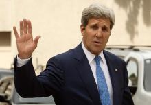 U.S. Secretary of State John Kerry waves to journalists as he walks to a meeting on the second straight day of talks over Tehran's nuclear program at a hotel in Vienna