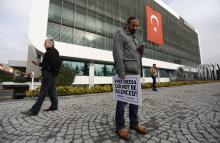 A Zaman media group journalist holds a banner as he stands outside the headquarters of Zaman daily newspaper in Istanbul, December 14, 2014. PHOTO BY REUTERS/Murad Sezer