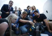 Journalists look at the monitor of a television camera crew who shot footage onboard a P-3 Orion aircraft of objects in the southern Indian Ocean, during a search of the missing Malaysian Airlines Flight MH370, after returning to RAAF Base Pearce in Bullsbrook, near Perth