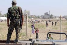 A Kurdish People's Protection Units (YPG) fighter looks at makeshift tents between the Syrian and Turkish borders of residents who fled Maskana town in the Aleppo countryside, as he stands in Tel Abyad town, Raqqa governorate, Syria, June 23, 2015. PHOTO BY REUTERS/Rodi Said
