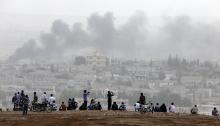 Turkish Kurds watch over the Syrian town of Kobani as they stand on top of a hill near Mursitpinar border crossing in the southeastern Turkish town of Suruc in Sanliurfa province
