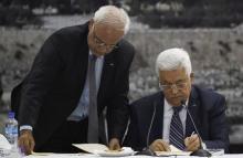 Palestinian chief negotiator Saeb Erekat (L) helps Palestinian President Mahmoud Abbas as he signs international conventions during a meeting with Palestinian leadership in the West Bank City of Ramallah, April 1, 2014. PHOTO BY REUTERS/Mohamad Torokman