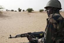A Malian soldier, holding an AK-47 rifle, rides in a pick-up truck during a military escort outside Timbuktu, Mali