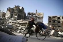 A handicapped man rides a bicycle past damaged buildings in the besieged town of Douma in eastern Ghouta in Damascus, Syria, March 1, 2018. PHOTO BY REUTERS/Bassam Khabieh