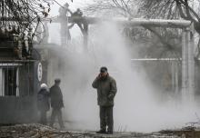 A man talks on a phone as workers repair a heating pipeline at a site hit by shelling in Donetsk, eastern Ukraine, February 1, 2015. PHOTO BY REUTERS/Maxim Shemetov