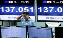 An employee of a foreign exchange trading company stands in front of monitors displaying the current exchange rate of the Japanese yen against the Euro in Tokyo, June 30, 2015. PHOTO BY REUTERS/Thomas Peter