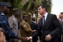 French Prime Minister Manuel Valls shakes hands with head of rapid intervention unit Commander Evrard Somda in front of Cappuccino cafe, the site of an Al Qaeda attack that killed 30 in January in Ouagadougou, Burkina Faso, February 20, 2016. PHOTO BY REUTERS/Nabila El Hadad