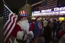 Matt Ornstein, dressed in a Santa Claus costume, holds an American flag as fans line up at the Silent Movie Theatre for a midnight screening of "The Interview" in Los Angeles, California, December 24, 2014. PHOTO BY REUTERS/Jonathan Alcorn