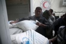 Men unload flour from a Red Crescent and United Nations aid convoy in the rebel held besieged town of Hamoria area, in the eastern suburbs of Damascus, Syria, April 19, 2016. PHOTO BY REUTERS/Bassam Khabieh