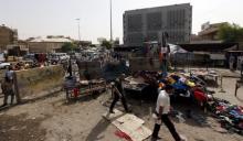 Men walk past the site of a suicide bomb attack in Baghdad, Iraq, September 17, 2015. At least 12 people were killed when three bombs went off in mainly Shi'ite neighborhoods in central Baghdad on Thursday, security and medical sources said. PHOTO BY REUTERS/Ahmed Saad