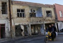 Men drive past a building which was damaged during the security operations and clashes between Turkish security forces and Kurdish militants, in the southeastern town of Silvan in Diyarbakir province, Turkey, December 7, 2015. PHOTO BY REUTERS/Murad Sezer