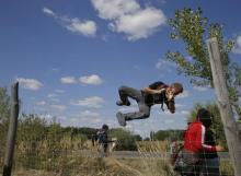 A migrant jumps over a road protection fence as they leave a collection point in the village of Roszke, Hungary, September 9, 2015. PHOTO BY REUTERS/Marko Djurica