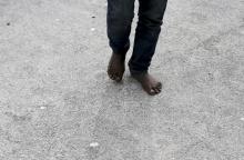 A migrant walks barefoot after arriving by boat at the Sicilian harbour of Pozzallo, February 16, 2015. PHOTO BY REUTERS/Alessandro Bianchi