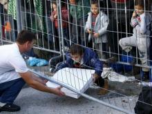 A waiter serves a pizza to a group of migrants waiting at the Austrian Slovenian border near the village of Sentilj, Slovenia, October 25, 2015. PHOTO BY REUTERS/Leonhard Foeger
