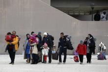 Migrants carry their belongings as they leave the Tae Kwon Do stadium at the southern suburb of Faliro in Athens, Greece, December 16, 2015. PHOTO BY REUTERS/Alkis Konstantinidis