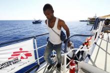 Migrants make their way to the upper deck of the Migrant Offshore Aid Station (MOAS) ship MV Phoenix after being rescued from an overloaded wooden boat (rear) 10.5 miles (16 km) off the coast of Libya, August 6, 2015. PHOTO BY REUTERS/Darrin Zammit Lupi