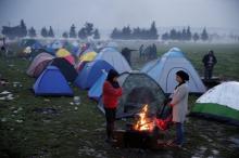 Migrants stand near fire at a makeshift camp set by stranded migrants waiting to cross the Greek-Macedonian border, near the Greek village of Idomenii, March 1, 2016. PHOTO BY REUTERS/Marko Djurica