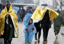 Migrants shelter themselves from the rain at a makeshift camp on the Greek-Macedonian border, near the village of Idomeni, Greece, March 13, 2016. PHOTO BY REUTERS/Stoyan Nenov