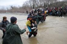 Migrants wade across a river near the Greek-Macedonian border, west of the the village of Idomeni, Greece, March 14, 2016. PHOTO BY REUTERS/Stoyan Nenov