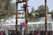 A Pakistani migrant climbs a utility pole during a demonstration inside the Moria registration centre on the Greek island of Lesbos, April 6, 2016. PHOTO BY REUTERS/Giorgos Moutafis