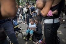 A newly arrived migrant holds her child as she waits to apply for asylum at the State Office for Health and Social Affairs in Berlin, Germany, August 10, 2015. PHOTO BY REUTERS/Stefanie Loos