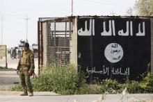 A member of militias known as Hashid Shaabi stands next to a wall painted with the black flag commonly used by Islamic State militants, in the town of al-slam, March 10, 2015. PHOTO BY REUTERS/Thaier Al-Sudani
