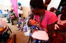 A mother, with her baby, picks up food at the internally displaced persons camp in Regent, Sierra Leone, August 19, 2017. PHOTO BY REUTERS/Afolabi Sotunde