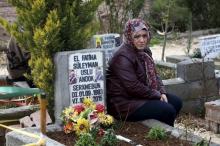 The mother of Suleyman Uslu sits next to the grave of her son, a People's Protection Units (YPG) member who was killed during fighting against Islamic State in north Syria, at a cemetery in Diyarbakir Turkey February 25, 2016. REUTERS/Sertac Kayar