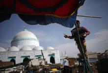 A Muslim man uninstalls a light from a temporary tent in front of a mosque in the Muslim dominated area in the western Indian city of Ahmedabad