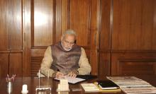 India's Prime Minister Narendra Modi signs a paper as he takes charge of the prime minister's office (PMO) at South Block in New Delhi