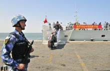 A navy soldier (L) of People's Liberation Army (PLA) stands guard as Chinese citizens board the naval ship "Linyi" at a port in Aden, March 29, 2015 file photo. PHOTO BY REUTERS/Stringer
