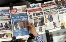 A man points at front pages of newspapers in central Athens, Greece, July 16, 2015. PHOTO BY REUTERS/Jean-Paul Pelissier