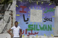 A Palestinian youth stands next to a wall painted with graffiti, outside a house which Jewish settlers moved into, in the east Jerusalem neighbourhood of Silwan September 30, 2014. PHOTO BY REUTERS/Baz Ratner