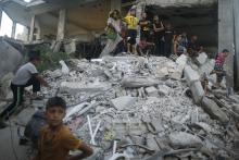 Palestinians look at a calf before it is slaughtered as they stand on the remains of a mosque, which witnesses said was hit by an Israeli air strike during a seven-week Israeli offensive, on the first day of the Muslim Eid al-Adha holiday in Gaza City