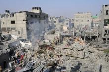 Palestinians stand on what witnesses say was a house destroyed by an Israeli air strike in Rafah, southern Gaza