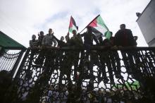 Palestinians hold Palestinian flags as they climb a gate during a rally calling on Egyptian authorities to open the Rafah border crossing, at the crossing in the southern Gaza Strip, November 23, 2014. PHOTO BY REUTERS/Ibraheem Abu Mustafa