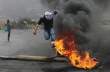 A Palestinian protester jumps past a burning tyre during clashes with Israeli troops during clashes near the Jewish settlement of Bet El, near the West Bank city of Ramallah, October 27, 2015. PHOTO BY REUTERS/Mohamad Torokman