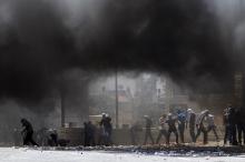 Palestinians hurl stones, as smoke rises from tyres they have set ablaze, during clashes with Israeli police in Shuafat, an Arab suburb of Jerusalem
