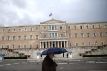 A man holding an umbrella makes his way in front of the Greek parliament during rainfall in Athens, January 29, 2015. PHOTO BY REUTERS/Alkis Konstantinidis