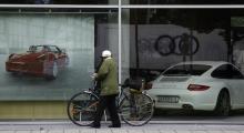 A unidentified pedestrian walks past a shopping window of a Porsche car dealer in Munich June 22, 2009. Facing an expected rejection from Berlin for its state loan request and in need of a capital infusion, heavily indebted Porsche SE could be running out of options to repair its sagging balance sheet. PHOTO BY REUTERS/Michael Dalder