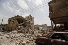People sit near houses destroyed by a Saudi-led air strike in Yemen's capital Sanaa, July 3, 2015. PHOTO BY REUTERS/Khaled Abdullah