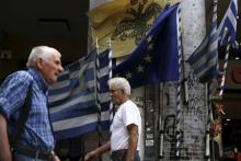 People make their way next to Greek national flags and a European Union flag in Athens, August 27, 2015. PHOTO BY REUTERS/Alkis Konstantinidis
